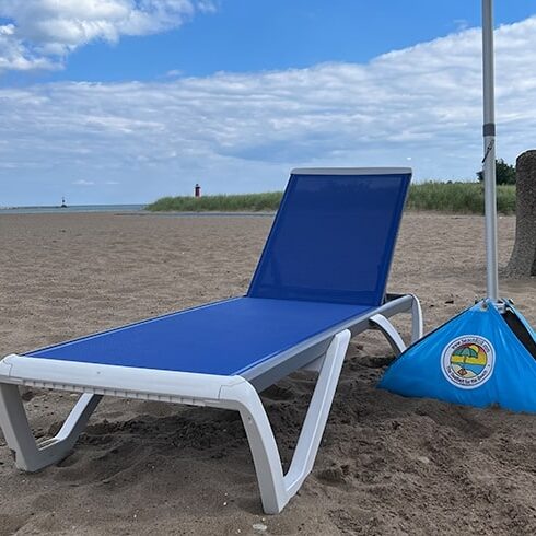 A chaise lounge and large umbrella on a beach
